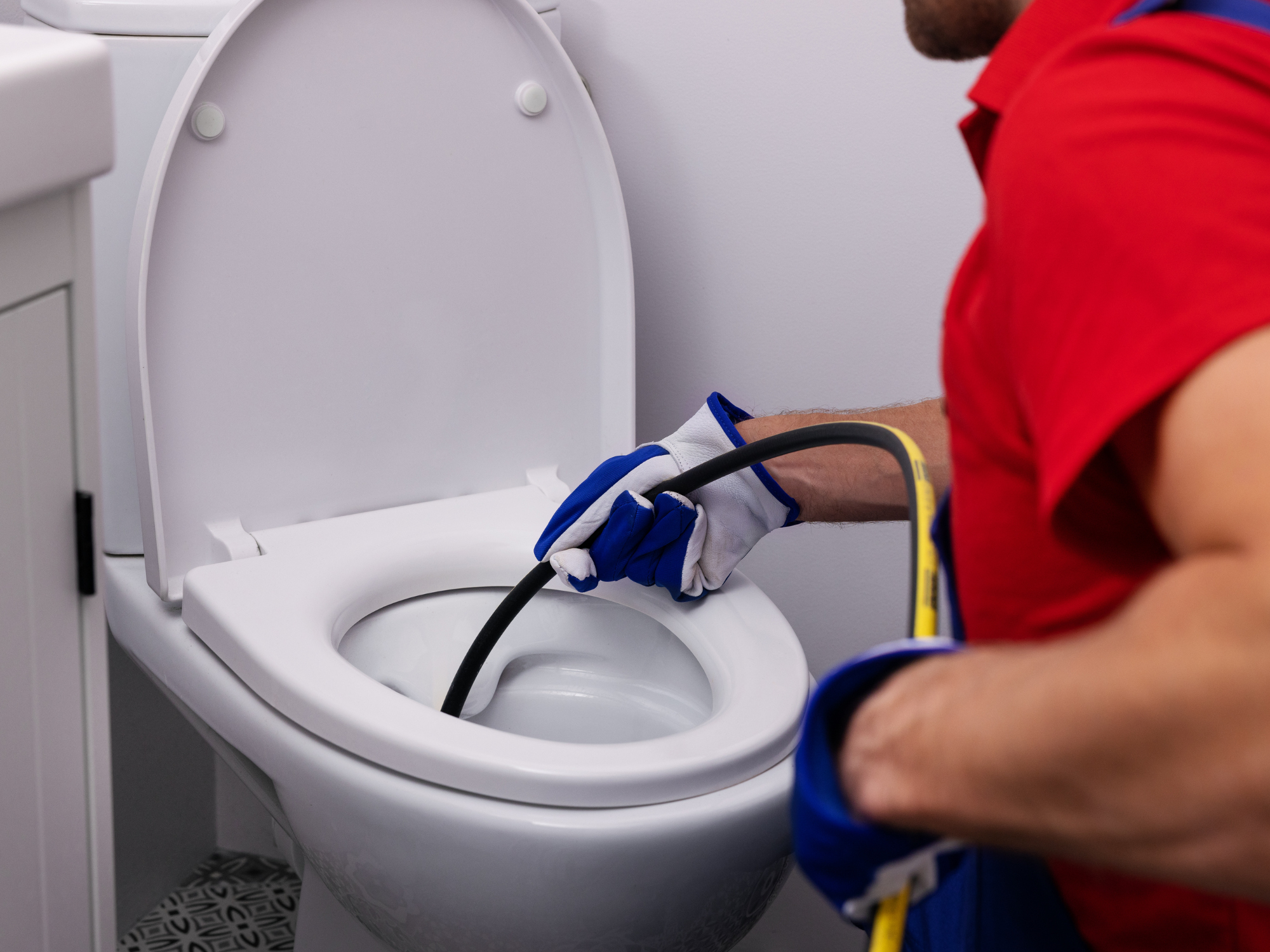 Plumber using specialised tool to clear a toilet blockage